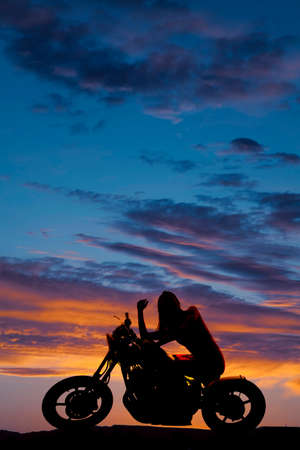 a silhouette of a woman sitting on her motorcycle  enjoying the night sky.の写真素材