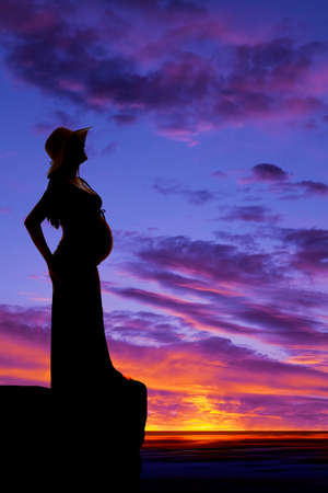 A silhouette of a woman who is pregnant standing on a ledge.の写真素材