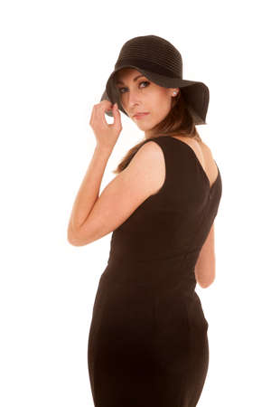 a woman in her black dress touching the brim of her hat.の写真素材