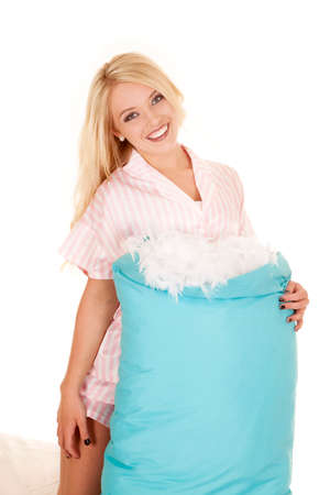 a woman in her pajamas with a smile on her face holding on to her pillow.の写真素材
