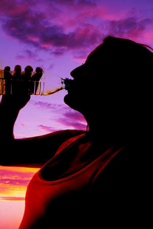 A silhouette of a woman drinking her water in the outdoor.の写真素材