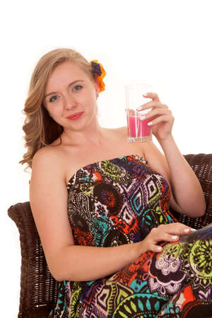 a woman sitting in a chair drinking a drink of something.の写真素材