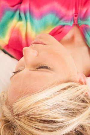 A woman in her colorful pajamas laying down looking to the side.の写真素材
