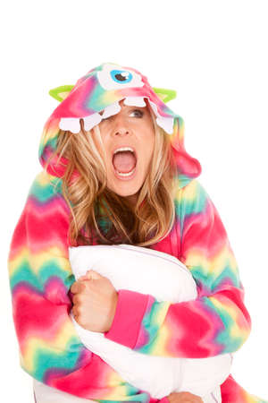 A woman in her monster pajamas holding on to a pillow with a funny expression.の写真素材