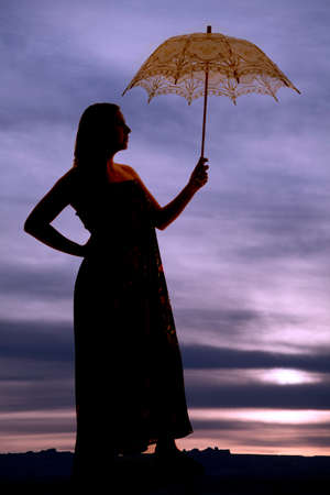 a silhouette of a woman in the outdoors holding up her umbrella.の写真素材