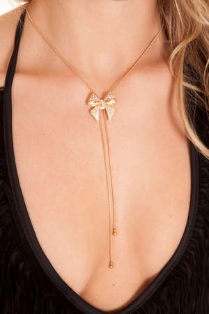 A close up of a woman wearing a gold bow necklace.の写真素材