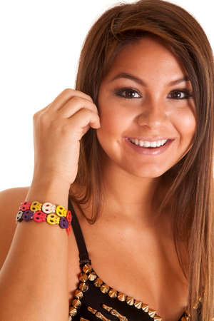 A close up of a woman with a smile on her face, wearing a multi-colored skull bracelet around her wrist.の写真素材