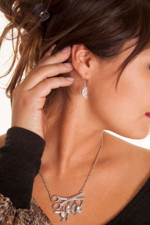 A woman looking down, she is wearing a earing that is a comb and a necklace.の写真素材