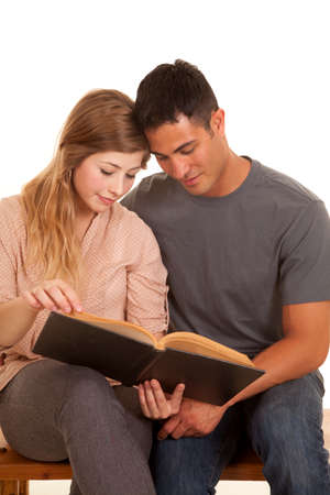 A couple sitting together reading a book with their heads together.の写真素材