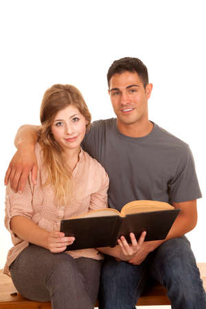 A couple sitting and reading a book looking at the camera.の写真素材