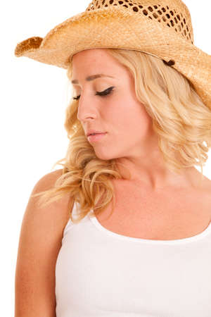A cowgirl in her white tank top and cowgirl hat looking down.の写真素材