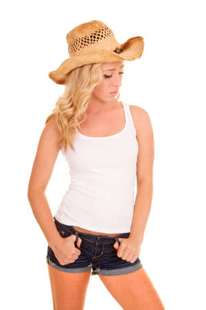 A cowgirl with her thumbs in her belt loops looking down.の写真素材