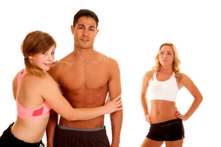 A woman holding on to her mans body while a woman in the background is unhappyの写真素材