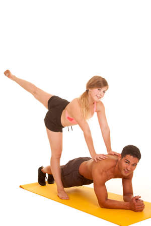 A man is in plank while his girl is pushing on him with her leg up.の写真素材
