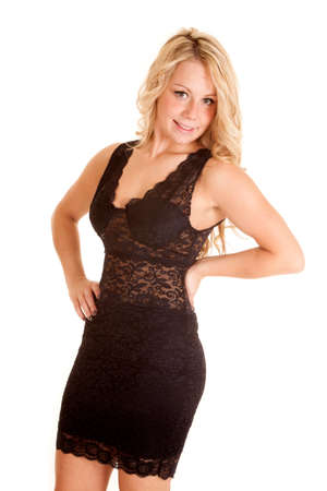 A woman in her lace short dress with her hand on her hip and a smile on her lips.の写真素材