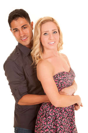 A man with his arms around his woman with a smile on his lips.の写真素材