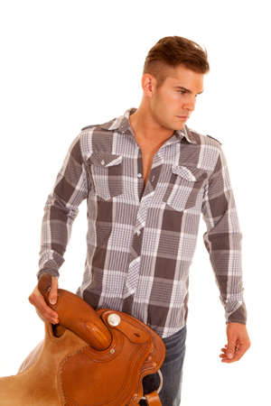 A cowboy holding onto his hat and his sadde with a serious expression.の写真素材