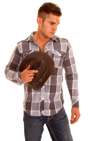 a cowboy looking down holding onto his hat.の写真素材