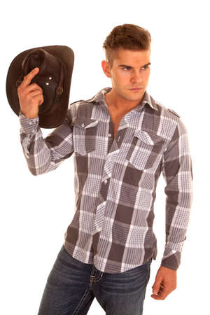 A cowboy looking to the side holding up his western hat.の写真素材