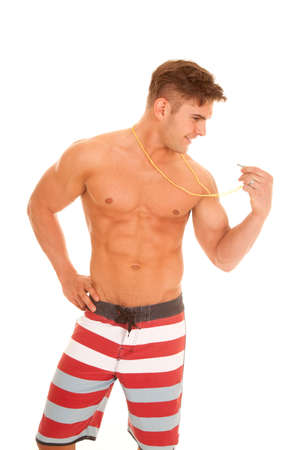 a man in his swim shorts looking at his whistle.の写真素材