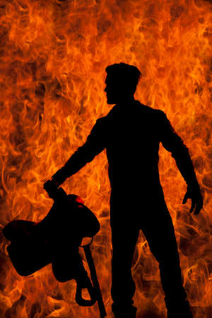 a silhouette of a cowboy holding onto his saddle with a fire background.の写真素材
