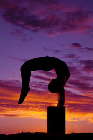 a woman doing a back bend off of the ground.の写真素材