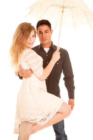 A woman and man with small smiles under an umbrella, holding on to his woman close.の写真素材