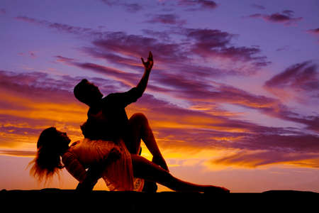A silhouette of a man and woman posing in a dance pose looking upの写真素材