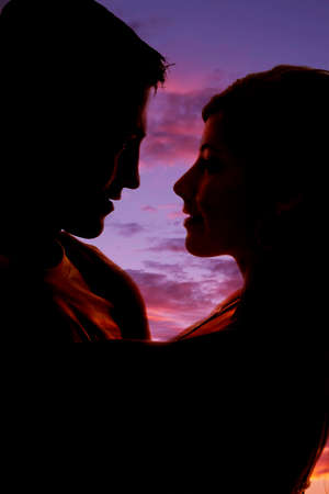 A silhouette of a man and woman wtih their faces close,, looking at each otherの写真素材