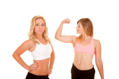 two women posing in their fitness clothing, one is flexing her muscles.の写真素材