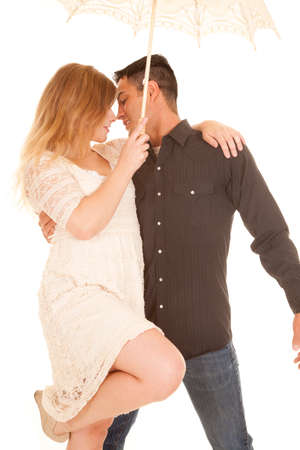 A couple standing together under an umbrella, almost kissing.の写真素材
