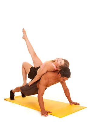 A woman laying on the back of a man while he is doing a push up.の写真素材
