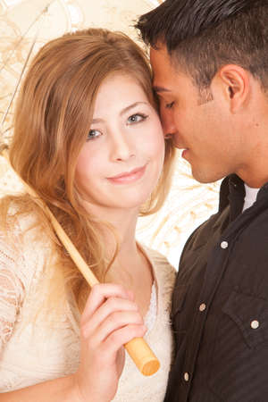 a woman and mans heads together under her umbrella.の写真素材
