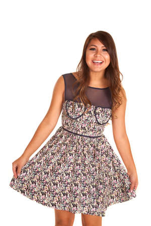 A woman playing with the bottom of her dress with a smile.の写真素材