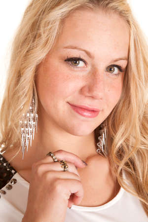 A woman with a smile on her face, she is wearing bronze rings on her fingers, and silver dangling earrings.の写真素材