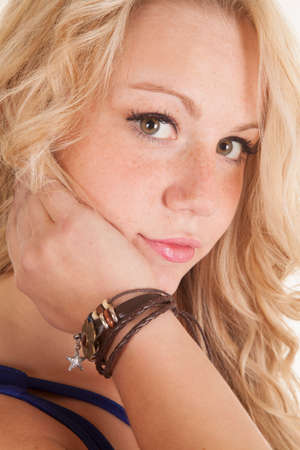 A close up of a blond woman looking, with her hand on her chin. She is wearing a bracelet.の写真素材