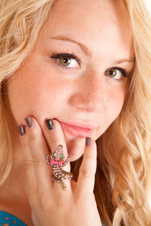 A close up of a woman looking, with her hand up by her face, wearing a gecko ring.の写真素材