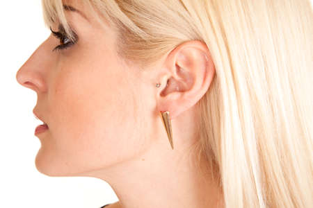 a the side of a woman's face wearing a gold cone earring.の写真素材