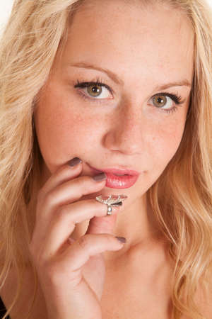 A woman looking with her fingers up by her face, wearing a nail ring.の写真素材