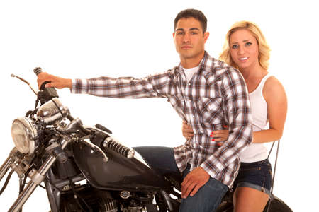 A woman hanging on to her man on the back of a motorcycle.の写真素材