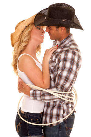 A cowboy getting ready to lean in for a kiss on his cowgirl.  They are tied up by a rope.の写真素材