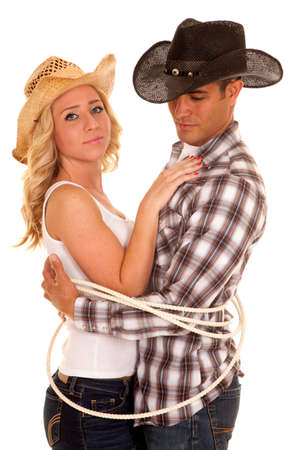 A cowboy and cowgirl tired up with a rope, getting close.の写真素材
