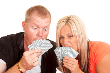 a man and woman with funny expressions looking at their playing cards.の写真素材