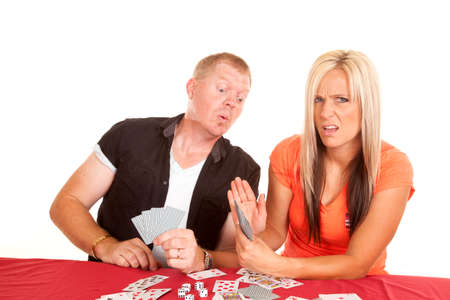 A man and woman playing cards, the man is trying to peek at the woman's cards.の写真素材