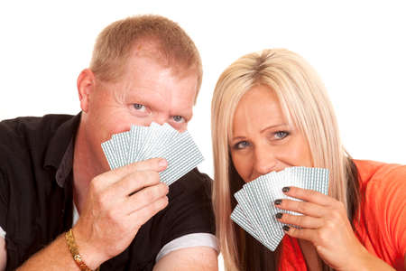 A man and woman leaning heads close, while their mouths are covered by playing cards.の写真素材