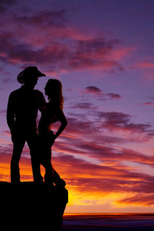 A silhouette of a cowboy holding on to his woman in the outdoors.の写真素材