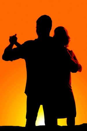 A silhouette of a man and woman dancing in the yellow sunset.の写真素材