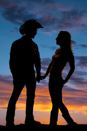 A silhouette of a cowboy and his woman holding hands in the outdoors.の写真素材