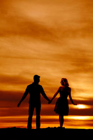 a silhouette of a man and woman holding hands with each other, walking together.の写真素材