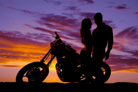 A silhouette of a man and woman next to a motorcycle in the outdoors.の写真素材